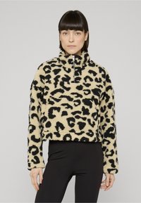 Pullover in pile con stampa leopardata, collo alto, chiusura con zip, macchie nere su sfondo beige, design corto e maniche lunghe.