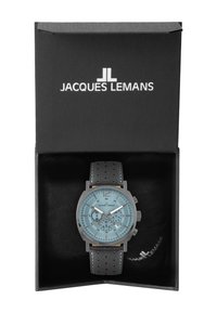 Orologio Jacques Lemans in una scatola nera. Caratterizzato da un quadrante azzurro chiaro, cassa grigia, cinturino in pelle nera perforata e dettagli in argento.