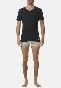 Svart V-ringad t-shirt i bomullstyg, kombinerad med grå boxershorts. T-shirten har en logotyp på den nedre vänstra sidan.