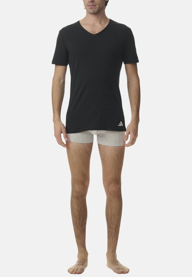 Svart V-ringad t-shirt i bomullstyg, kombinerad med grå boxershorts. T-shirten har en logotyp på den nedre vänstra sidan.