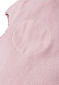 Tessuto di cotone rosa chiaro con una consistenza morbida, caratterizzato da un particolare patch circolare cucito sulla superficie, tagliato in un design senza maniche.