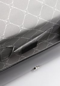 Interno di una borsa in pelle nera con rivestimento grigio caratterizzato da un motivo geometrico. Include una tasca a scomparsa e una chiusura con gancetto metallico.
