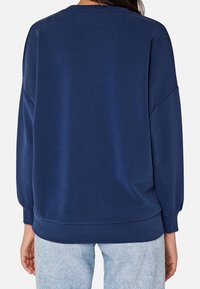 Felpa blu navy con collo rotondo, spalle scese e orlo a costine. Realizzata in tessuto morbido e liscio con vestibilità comoda.