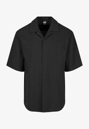 Crna majica kratkih rukava s teksturiranim uzorkom, šiljastim ovratnikom i prednjim džepom. Zatvaranje gumbar s prednje strane.