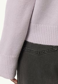 Helles lavendelfarbenes Strickpullover mit gerippten Bündchen, Saum und einer lockeren Passform, kombiniert mit grauen Jeans. Die Textur wirkt weich und gemütlich.