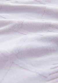 Baltas, tekstūruotas audinys su subtiliu raštu, demonstruojantis minkštus pluoštus ir lygų paviršių. Medžiaga atrodo lengva ir lanksti.