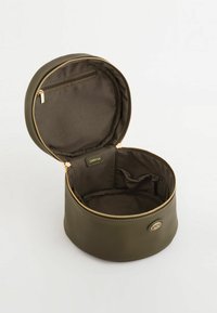 Rund olivengrøn kosmetikpose lavet af tekstureret materiale med en guldlynlås, der har en indvendig lomme og et logomærke indeni.