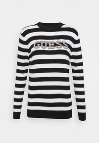 Pull rayé noir et blanc à manches longues, col côtelé, avec un logo "GUESS" en sequins sur la poitrine.