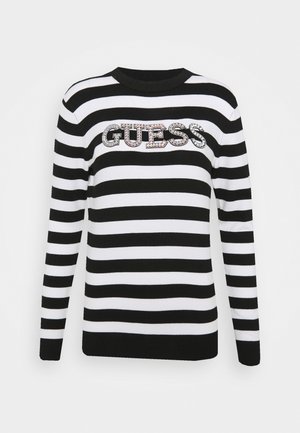 Pull rayé noir et blanc à manches longues, col côtelé, avec un logo "GUESS" en sequins sur la poitrine.