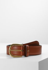 Bruine leren riem met een gouden metalen gesp. Heeft een gladde textuur en een enkelpuntsontwerp. Stiksels zichtbaar langs de randen.