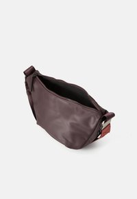 Mala bordo crossbody torba s patentnim zatvaračem i podesivim remenom s metalnom kopčom, prikazana prazna na bijeloj pozadini.