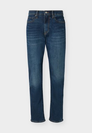 Dunkelblaue Jeans mit geradem Bein, Vordertaschen, Gürtelschlaufen, Knopf- und Reißverschluss, auf einfachem Hintergrund dargestellt.