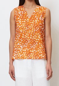 Top sin mangas en un patrón floral naranja y blanco, con un diseño de escote en V, hecho de tela ligera, con un corte recto y un ligero drapeado.