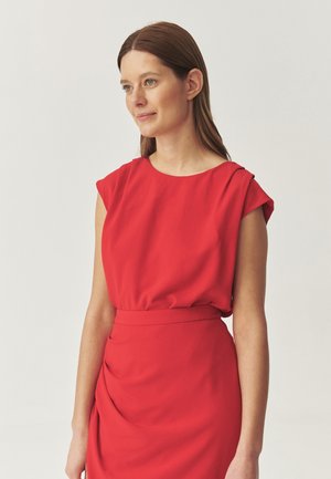 Punainen mekko, jossa on hihattomat hihat, istuva vyötärö ja laskostettu hame. Valmistettu kevyestä kankaasta, jossa on sileä pinta. Yksinkertainen ja elegantti muotoilu.