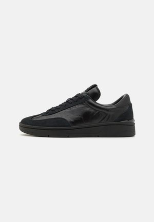 Sneakers noirs en cuir lisse et en daim, à bout arrondi, semelle plate, laçage à l'avant et col rembourré pour plus de confort.
