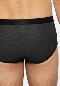 Sous-vêtements rayés noirs et gris avec une ceinture élastique noire, coupe ajustée et texture lisse conçue pour le confort.