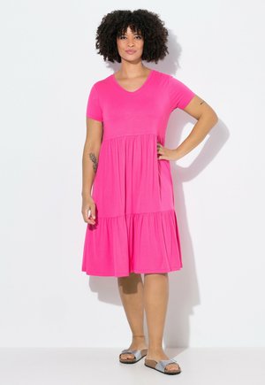 Rosa Kurzarmkleid mit einem gestuften Rock, aus einem weichen Stoff gefertigt. Verfügt über einen V-Ausschnitt und einen entspannenden Schnitt. Getragen mit flachen, silbernen Sandalen.