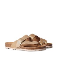 Brown sandals made of suede and metallic material. Crossed straps, adjustable buckle detail, cork footbed, and textured outsole.