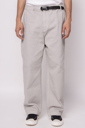 Light gray, wide-leg pants with an elastic waistband and black belt. Made of durable fabric, textured finish, complemented by black sneakers.