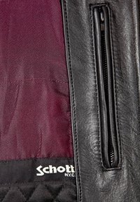 Eine schwarze Lederjacke mit einem kastanienbraunen Futter, ausgestattet mit einer Reißverschlusstasche und einem gesteppten Stoffdetail am Saum, versehen mit dem Etikett "Schott N.Y.C."