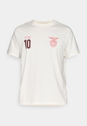 T-shirt in cotone color avorio con colletto rotondo. Presenta una stampa rossa con la scritta "O Rei" e il numero "10" sul lato sinistro del petto, oltre a un'emblema accanto ad essa.