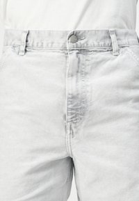Light gray denim pants with a button closure, belt loops, and a smooth texture. Features subtle fading and stitching details on the seams.