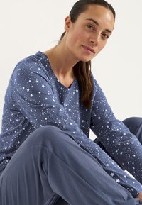 Paita pyjamaksi tummansinisistä pitkähihaisista, joissa on valkoinen tähtikuosi, yhdistettynä matching sinisiin housuihin, valmistettu pehmeästä puuvillamateriaalista.