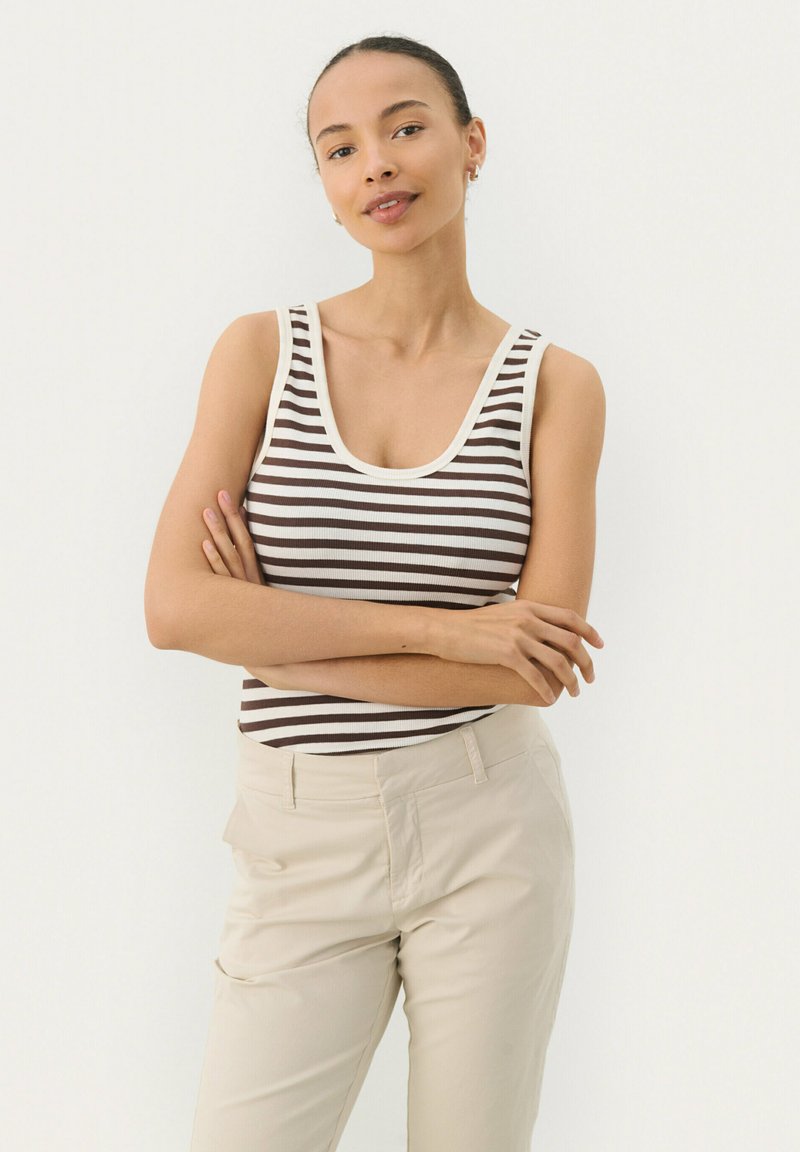 Gestreiftes Tanktop in Braun und Creme mit weitem Ausschnitt, kombiniert mit hellbeigen Hosen; der Stoff scheint glatt und leuchtend zu sein.