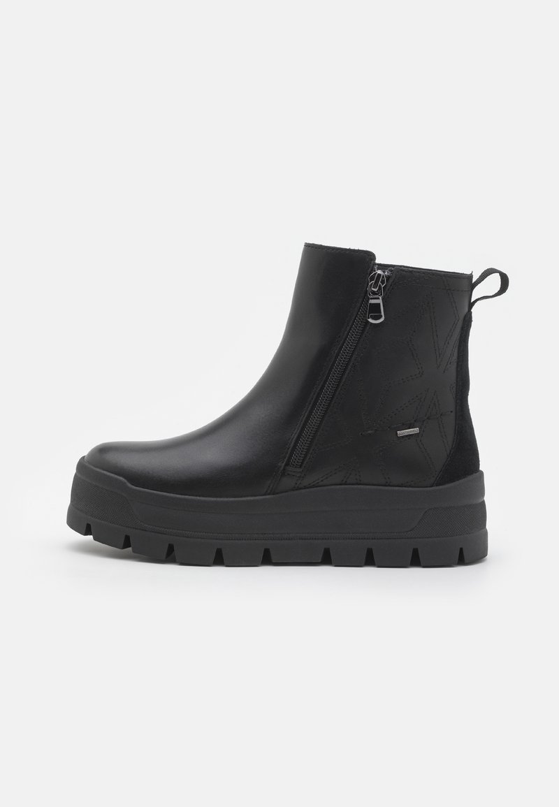 Bottine noire à cheville avec semelle épaisse rainurée, fermeture éclair latérale, languette au talon et motif discret cousu sur une tige en cuir lisse.