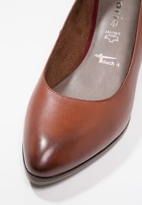 Ballerines pour femmes en cuir marron avec un bout rond et une semelle intérieure grise rembourrée, affichant des marques de la marque à l'intérieur.