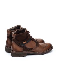 Stivali alla caviglia in pelle marrone con accentuazioni in suede, caratterizzati da una punta rotonda, lacci frontalmente e suola texturizzata. Dettagli cuciti lungo i bordi.