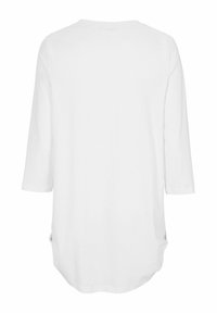 Witte top met 3/4 mouwen en ronde hals, gemaakt van zachte stof; beschikt over kleine zijslits en een langere achterzoom voor extra comfort en gemak.