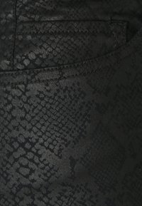 Cuero sintético negro con un patrón de piel de serpiente texturizado, con costuras visibles y un detalle de bolsillo en el borde.