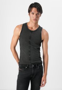 Top negru fără mâneci, fabricat dintr-un material moale, având un decolteu rotund, cusături contrastante și un design ajustat. Purtați cu blugi închiși la culoare.