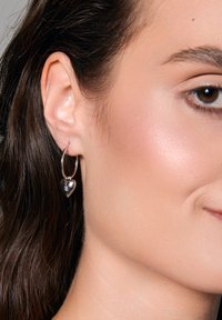 kolczyki kółka z srebrnym serduszkiem, z polerowanym wykończeniem i małym dekoracyjnym akcentem, zawieszone na standardowym kółku.