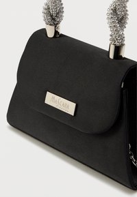 Czarna torebka z tkaniny z klapką, z metalowymi elementami w kolorze srebrnym oraz koralikowymi uchwytami. Wyróżniająca się płytka z logo z przodu.