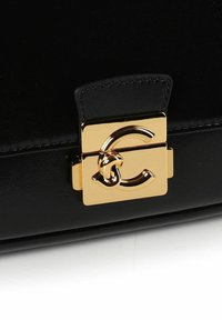 Zwarte leren handtas met een goudkleurige sluiting met een kenmerkend logodesign, een gladde textuur en een gestructureerde vorm.