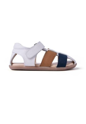 Sandalia de cuero blanco con detalles en marrón y azul marino, punta y laterales abiertos, correa ajustable, suela plana y diseño minimalista.