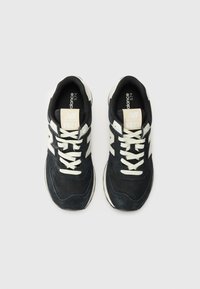 Baskets noires et marines avec une combinaison de matériaux en daim et en mesh, présentant des accents crème, des lacets et un logo sur la languette.