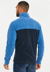 Blauer Fleece-Pullover mit dunkelblauem unteren Abschnitt, hohem Kragen, langen Ärmeln und einer strukturierten Oberfläche, geeignet für die Freizeit.
