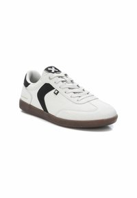 Zapatillas de ante gris claro con detalles en negro, punta redonda, diseño de cordones y suela de goma marrón. Presenta el logo en la lengüeta y el lateral.