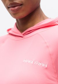 Ροζ φούτερ με κουκούλα από απαλό ύφασμα, με λευκό λογότυπο μπροστά, χαρακτηριστική κουκούλα και ραφές λεπτομέρειας.