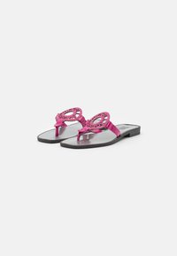 Vaaleanpunaiset litteät sandaalit, joissa on koristeellinen leikattu muotoilu remmeissä, ohut pohja ja sileä musta sisäpohja. Minimalistinen tyyli ilman koristuksia.