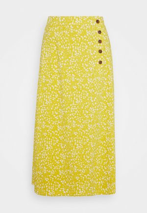Gul midi-nederdel med hvide abstrakte pletter, høj talje og fem brune knapper langs højre sides linning.