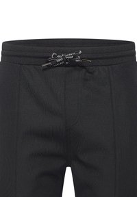 Black jogger pants with a textured finish, elastic waistband, and adjustable drawstring. Features front pockets and sleek cut.