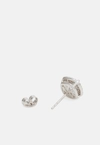 Brincos de prata com um design circular, apresentando padrões recortados e um pino reto. Inclui uma peça decorativa de apoio.