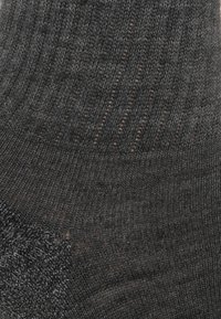 Calcetín negro de punto con un patrón acanalado texturizado en la parte superior y un material liso en la parte inferior, con una zona de puntera reforzada.