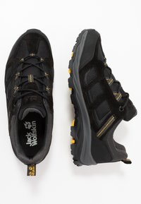 Scarpe da trekking nere realizzate in materiali mesh e suede, con accenti gialli, suola in gomma robusta e un design testurizzato per una migliore aderenza.
