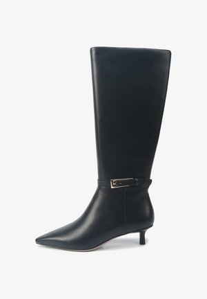 Bota de cuero negro hasta la rodilla con punta afilada, tacón estrecho y una correa delgada en el tobillo con un acento en tono dorado. Textura suave.