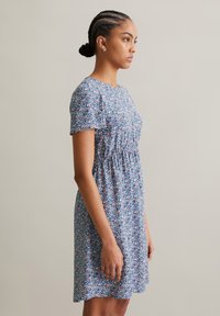 Blumenkleid aus leichtem Stoff, mit kurzen Ärmeln, einem runden Ausschnitt und einem taillierten Oberteil mit geraffter Taille in Blau-, Pink- und Grüntönen.